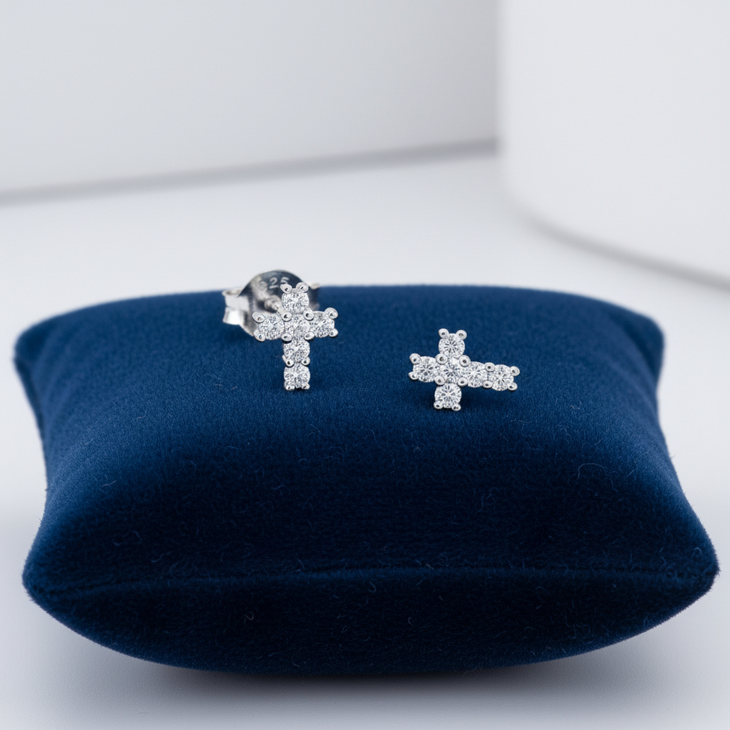 Melchior Jewellery cubic zirconia cross earrings for kids displayed on a navy blue cushion