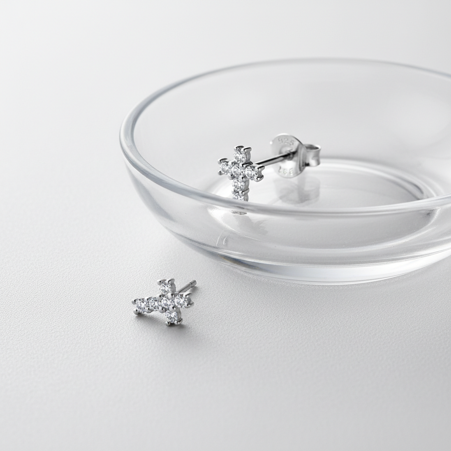Melchior Jewellery cubic zirconia cross earrings for kids displayed on clear glass dish on white surface