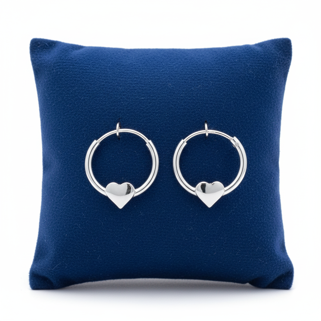 Melchior Jewellery girls heart charm hoop earrings in silver displayed on blue cushion