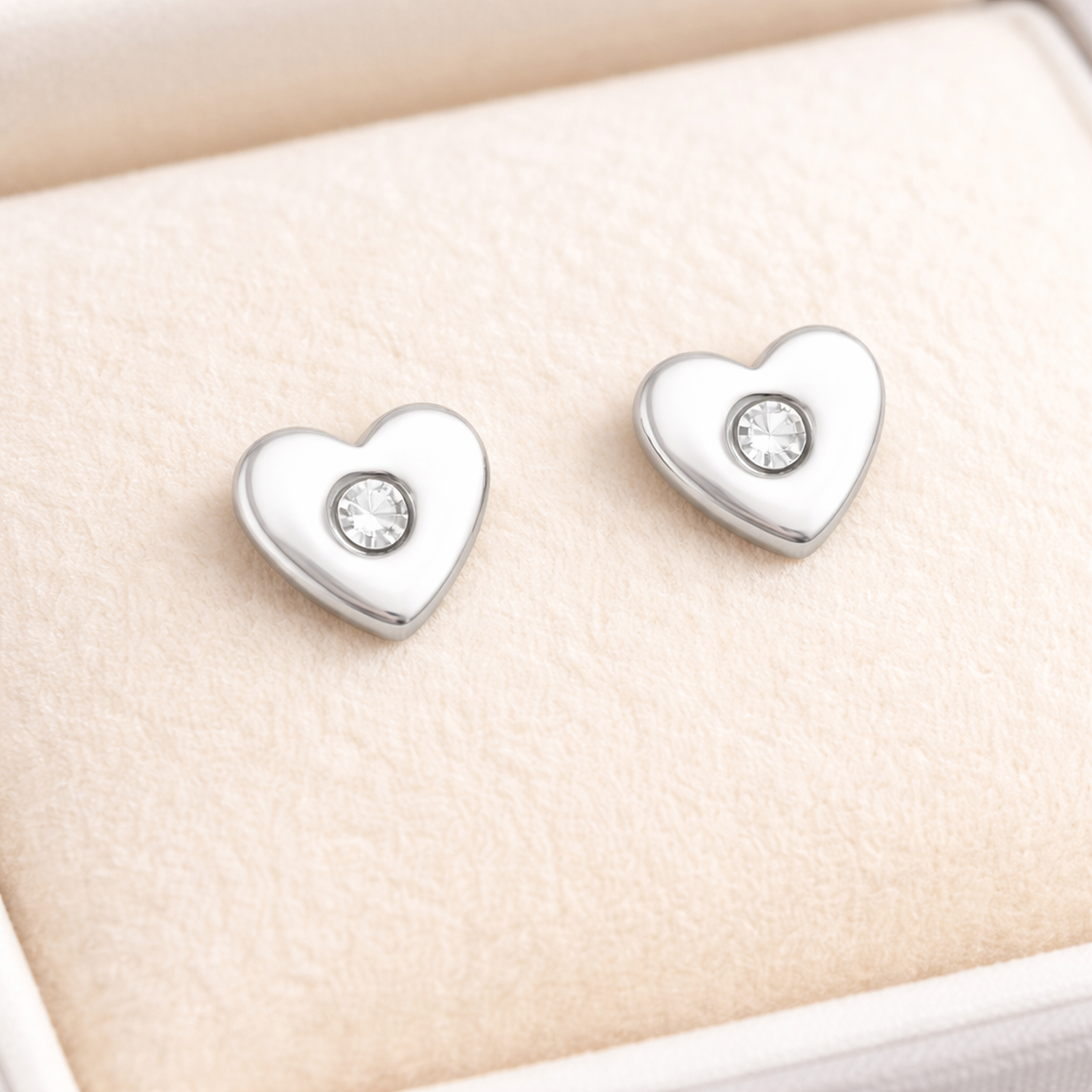 Melchior Jewellery heart shaped earrings for girls in silver with central clear stones on cream cushion