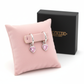Heart-shaped silver earrings for children with pink stones displayed on a pink cushion by Melchior Jewellery