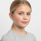 Young girl wearing heart-shaped silver earrings for children by Melchior Jewellery with pink accents