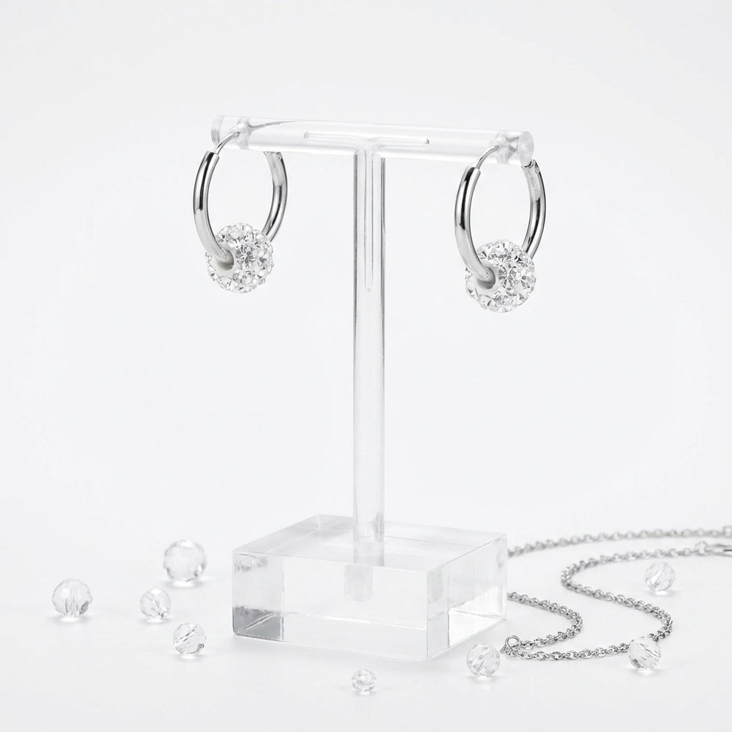 Silver kids crystal ball charm earrings with sparkling clear crystal balls displayed on a clear stand by Melchior Jewellery