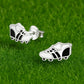 Melchior Jewellery kids football boot stud earrings in silver and black on green grass background