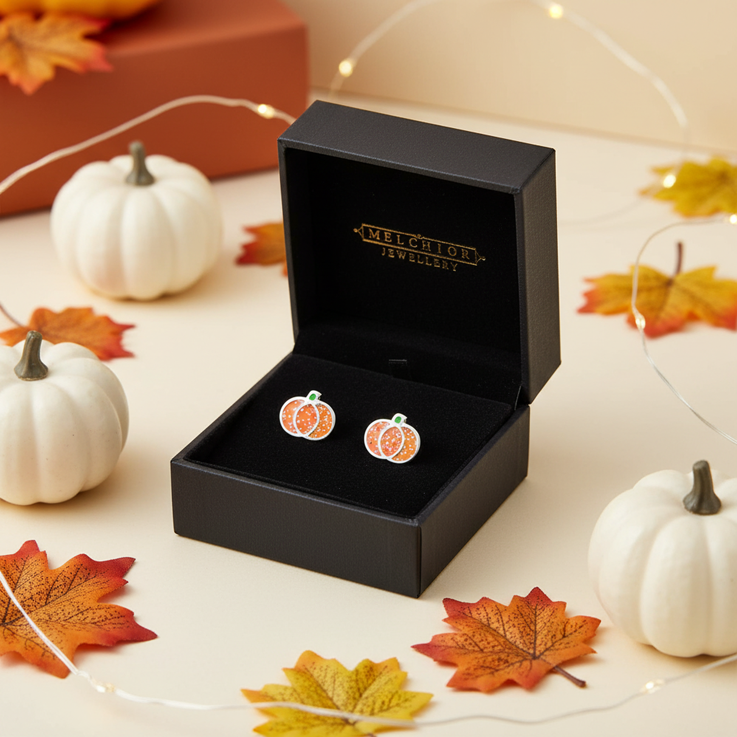 Kids glitter pumpkin stud earrings in sparkling orange and green in black Melchior Jewellery box with autumn leaves