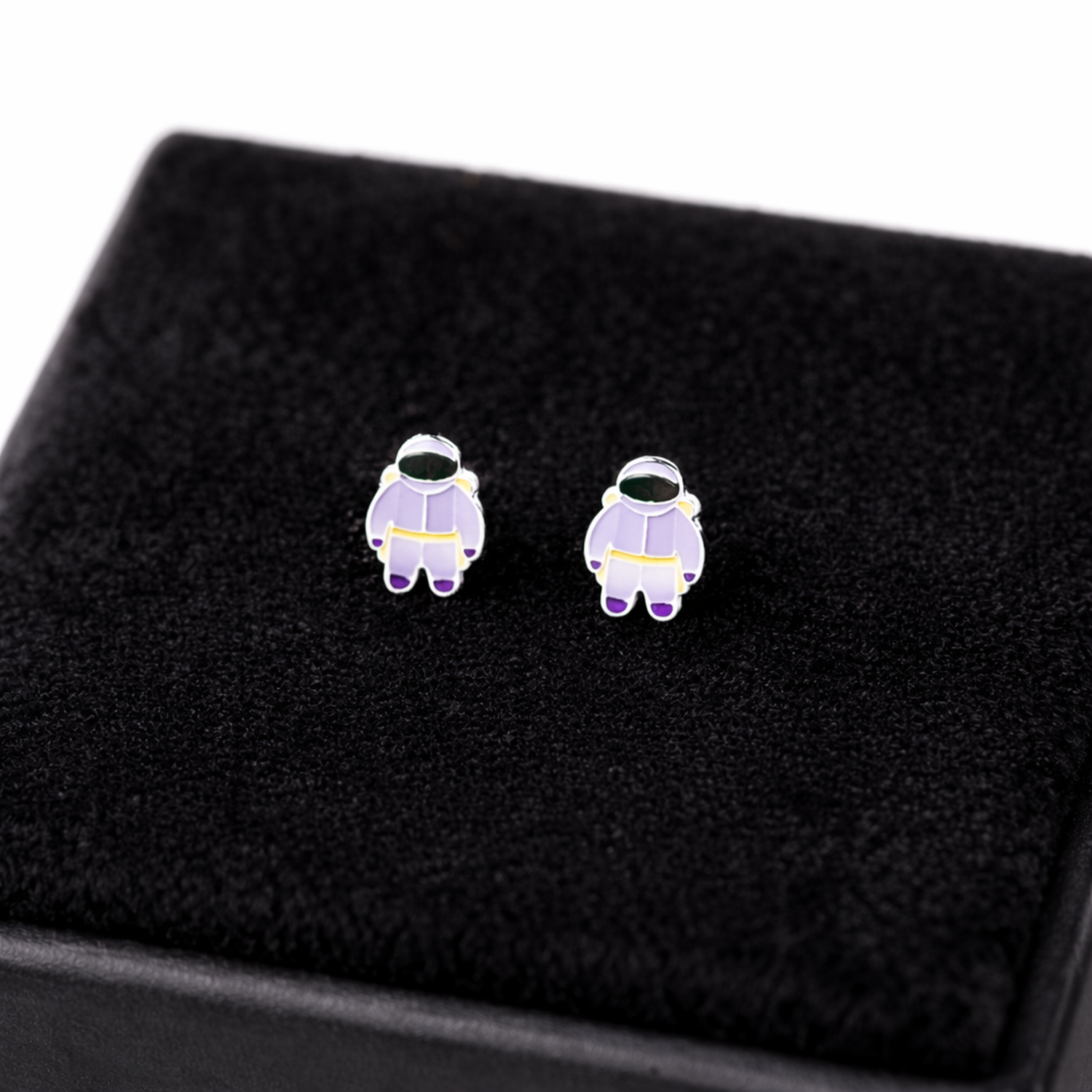 Melchior Jewellery kids hypoallergenic astronaut stud earrings in purple and white displayed on black cushion