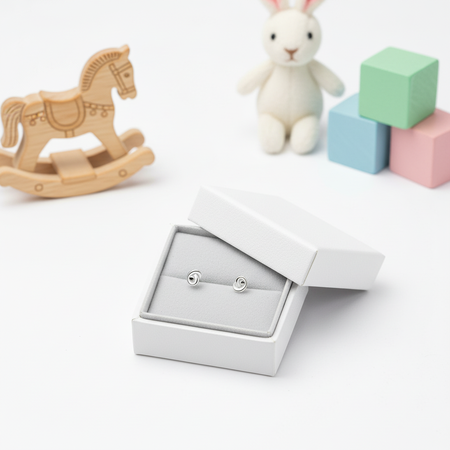 Melchior Jewellery kids safe silver knot studs in white box with wooden rocking horse and soft bunny toy
