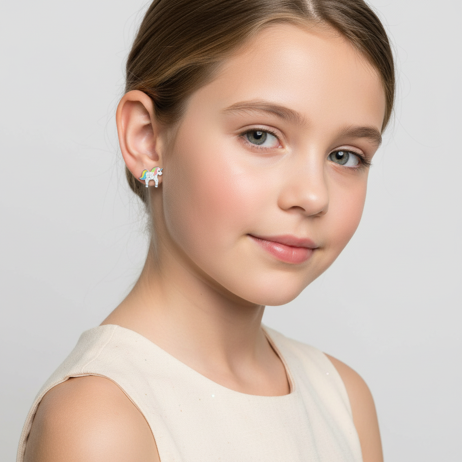 Young girl wearing kids white glitter unicorn stud earrings by Melchior Jewellery on white background