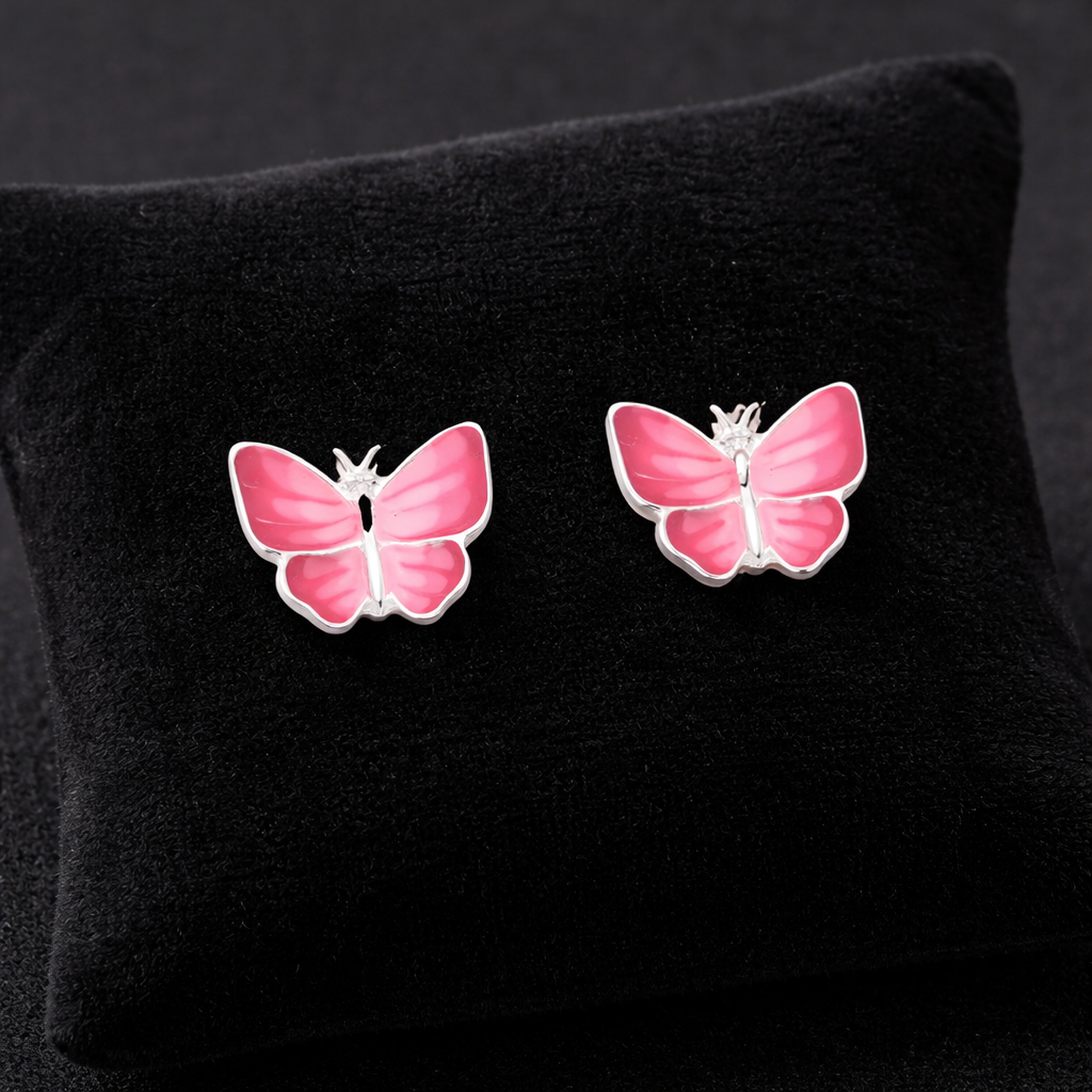 Melchior Jewellery pink butterfly stud earrings for kids on black cushion background