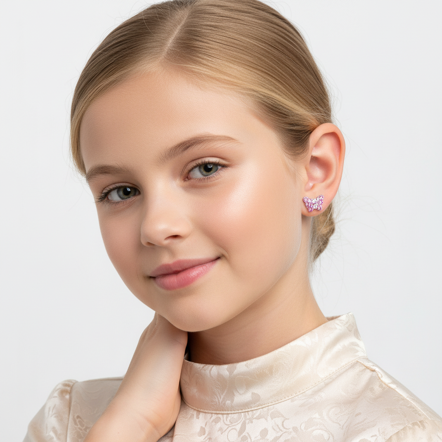 Young girl wearing pink butterfly stud earrings for kids from Melchior Jewellery with a soft smile