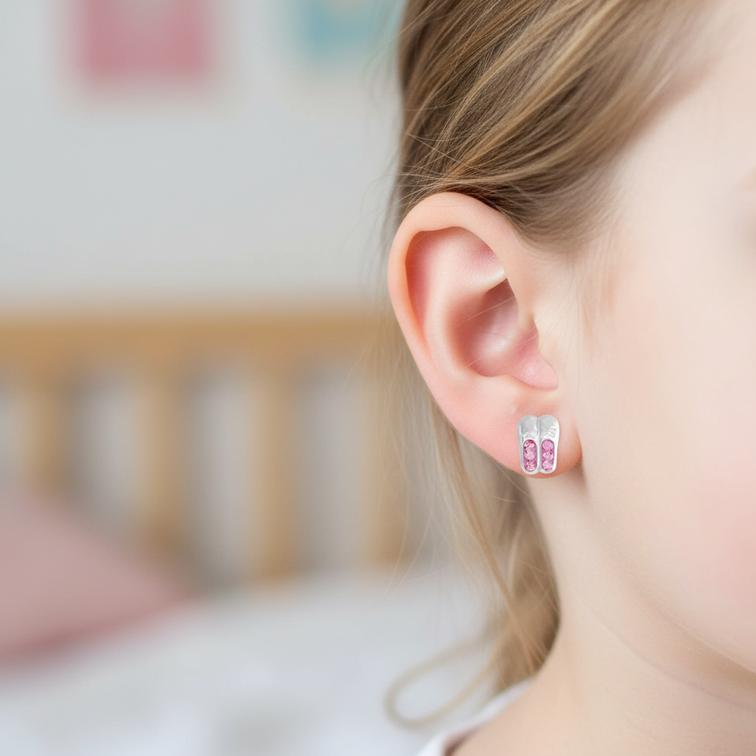 Melchior Jewellery childrens earrings featuring pink crown ballet shoes earrings worn on a young girl's ear