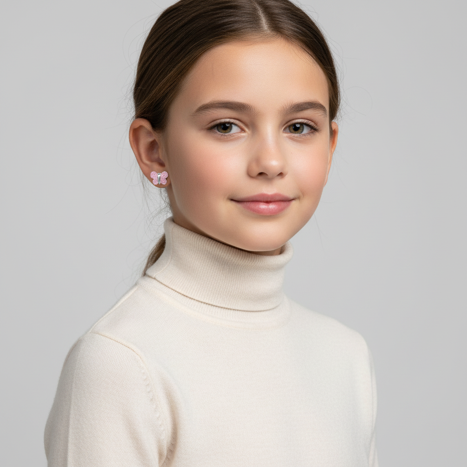 Girl wearing pink glitter butterfly stud earrings for kids by Melchior Jewellery with cream turtleneck