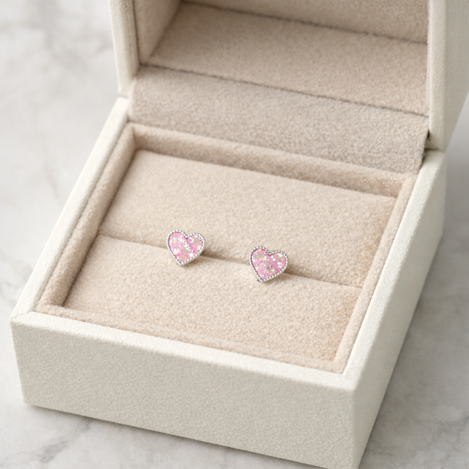 Melchior Jewellery pink glitter heart stud earrings for kids displayed in a cream jewellery box