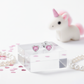 Pink heart earrings for girls by Melchior Jewellery displayed on clear block with unicorn toy and pearl bracelet