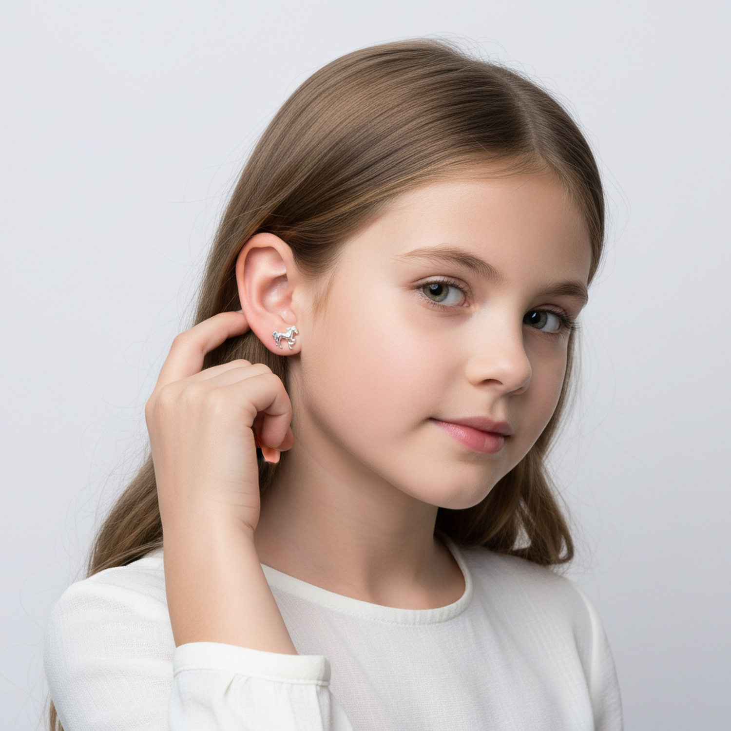 Young girl wearing premium kids silver animal earrings from Melchior Jewellery in a white top