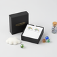 Silver rainbow earrings for girls displayed in Melchior Jewellery black box with colourful marbles and decorative cloud