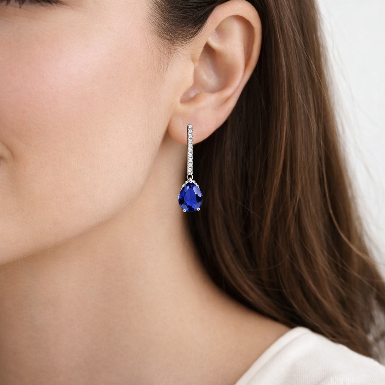 Silver Sapphire September Birthstone Earrings with deep blue teardrop sapphire on womans ear from Melchior Jewellery