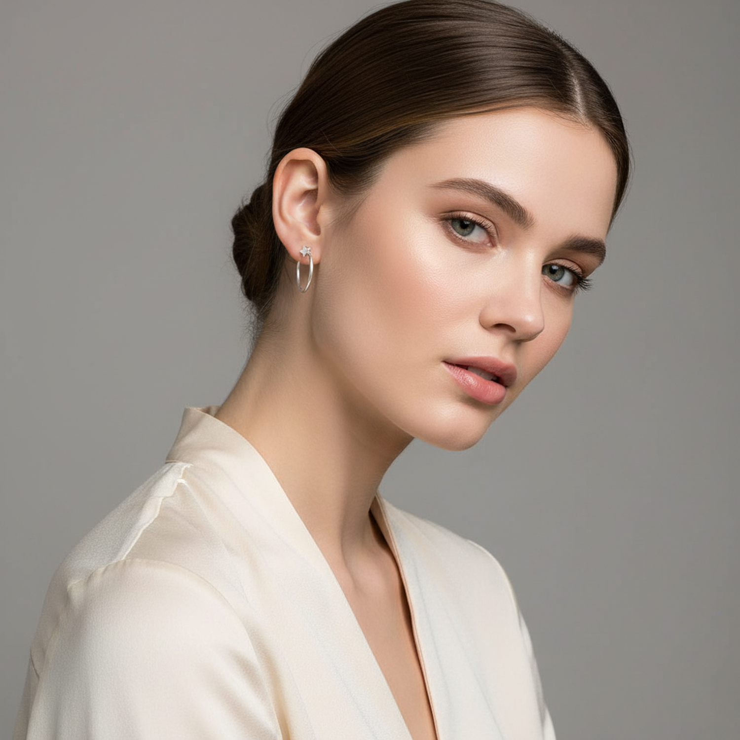 Melchior Jewellery small pull through star earrings worn by woman with sleek hairstyle and cream blazer