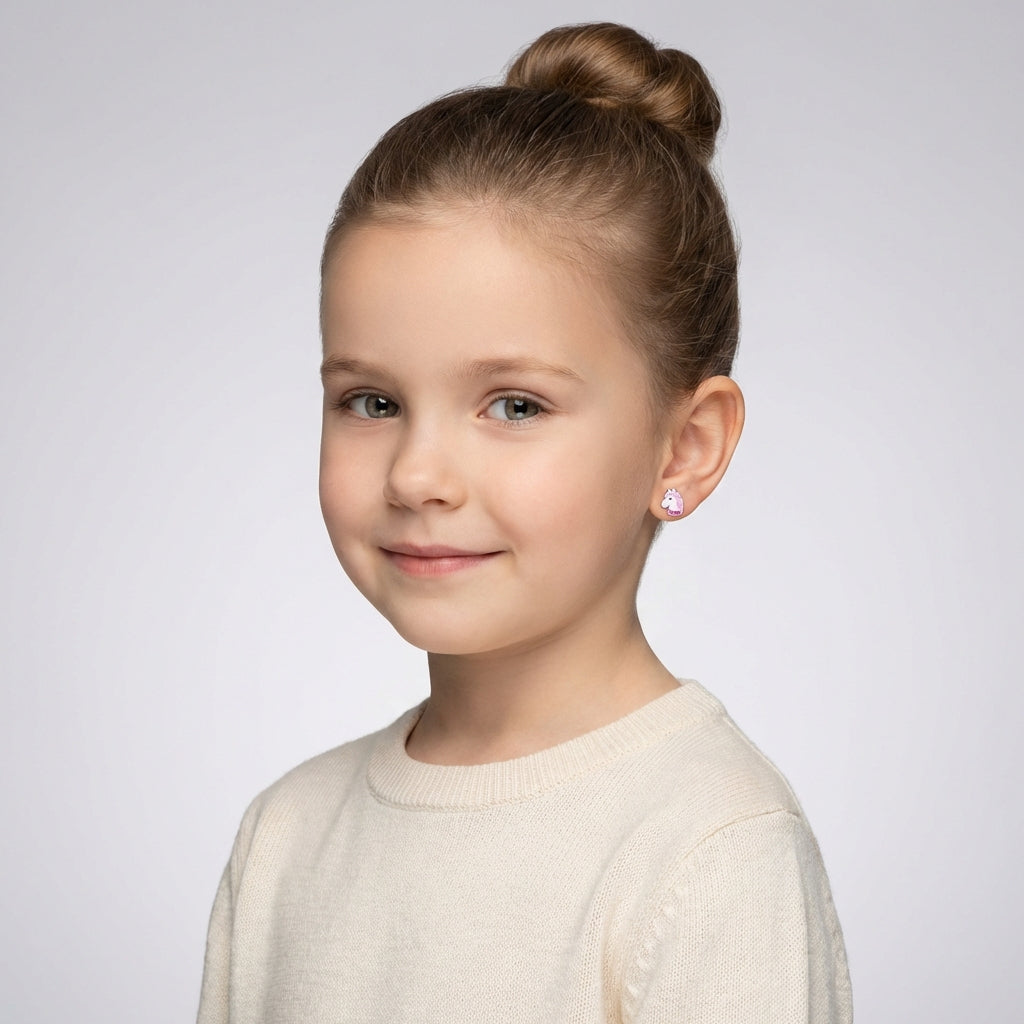 Child wearing sparkly pink unicorn earrings for kids from Melchior Jewellery with hair in a bun