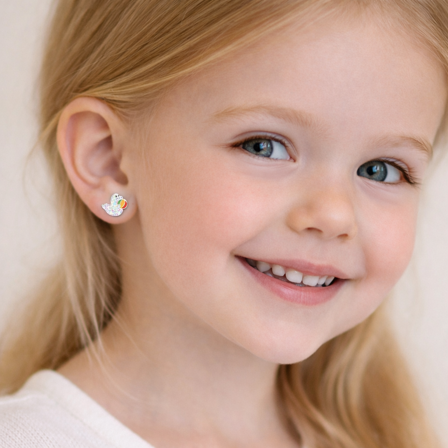 Girl wearing sparkly seal stud earrings for kids by Melchior Jewellery showing silver and colourful design