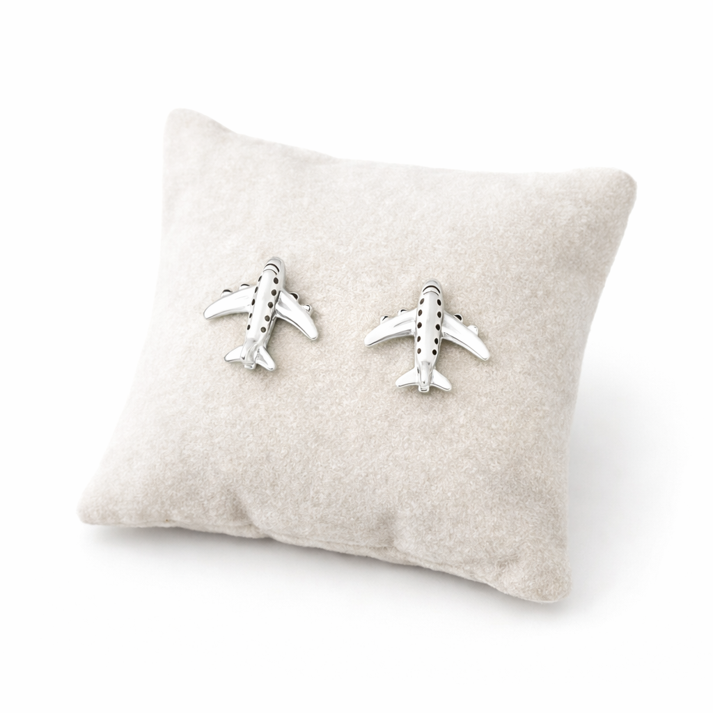 Sterling silver aeroplane earrings from Melchior Jewellery displayed on a soft beige cushion