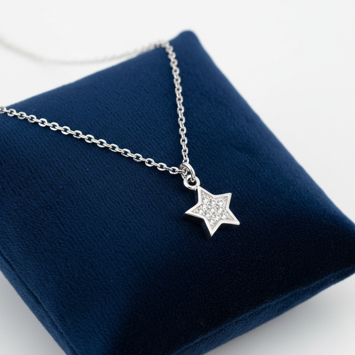 Sterling Silver CZ Star Pendant Necklace by Melchior Jewellery displayed on a navy blue cushion