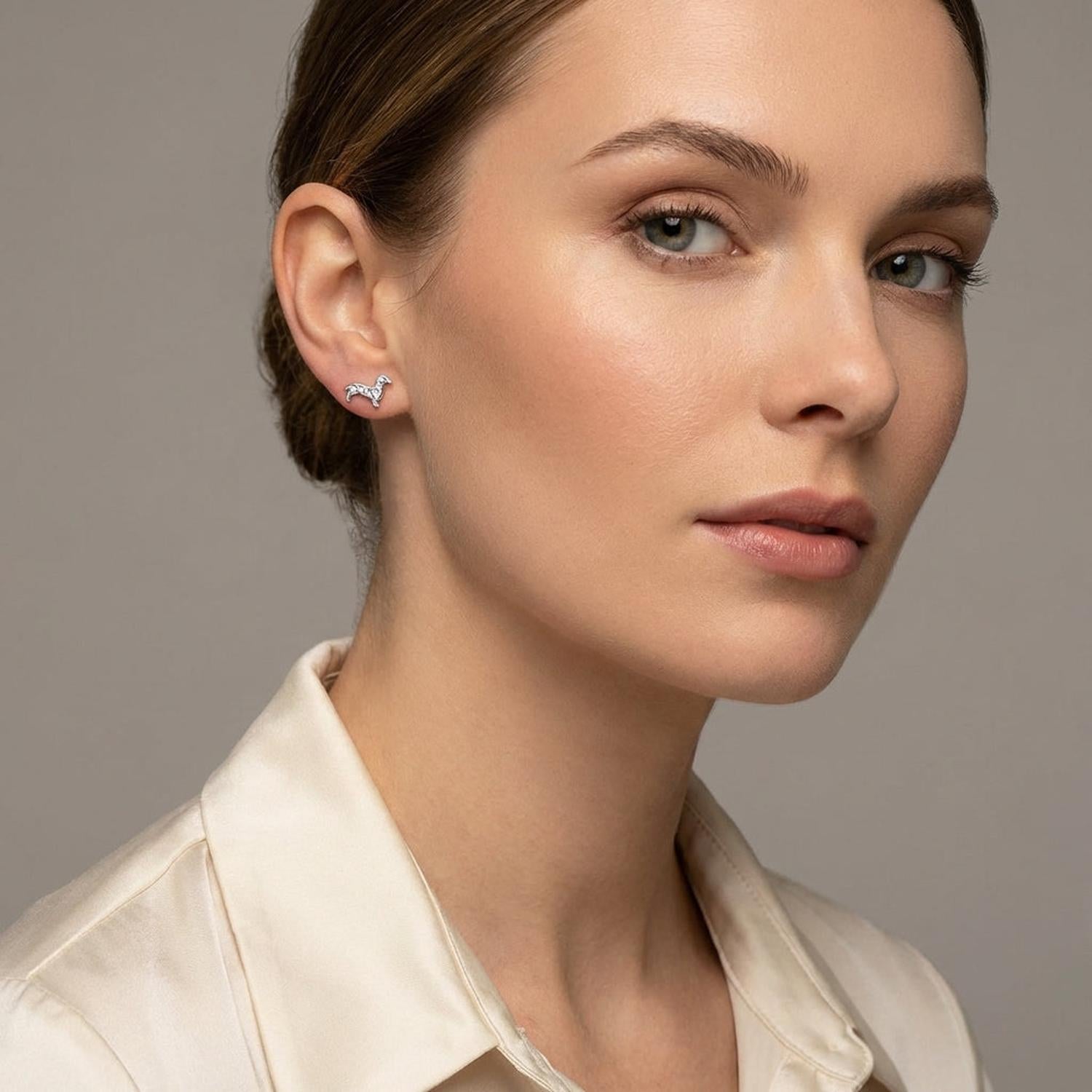 Melchior Jewellery sterling silver dachshund earrings worn by woman with neutral makeup and cream blouse