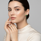 Sentiell sterling silver emerald green stud earrings worn by woman with neutral makeup and cream top
