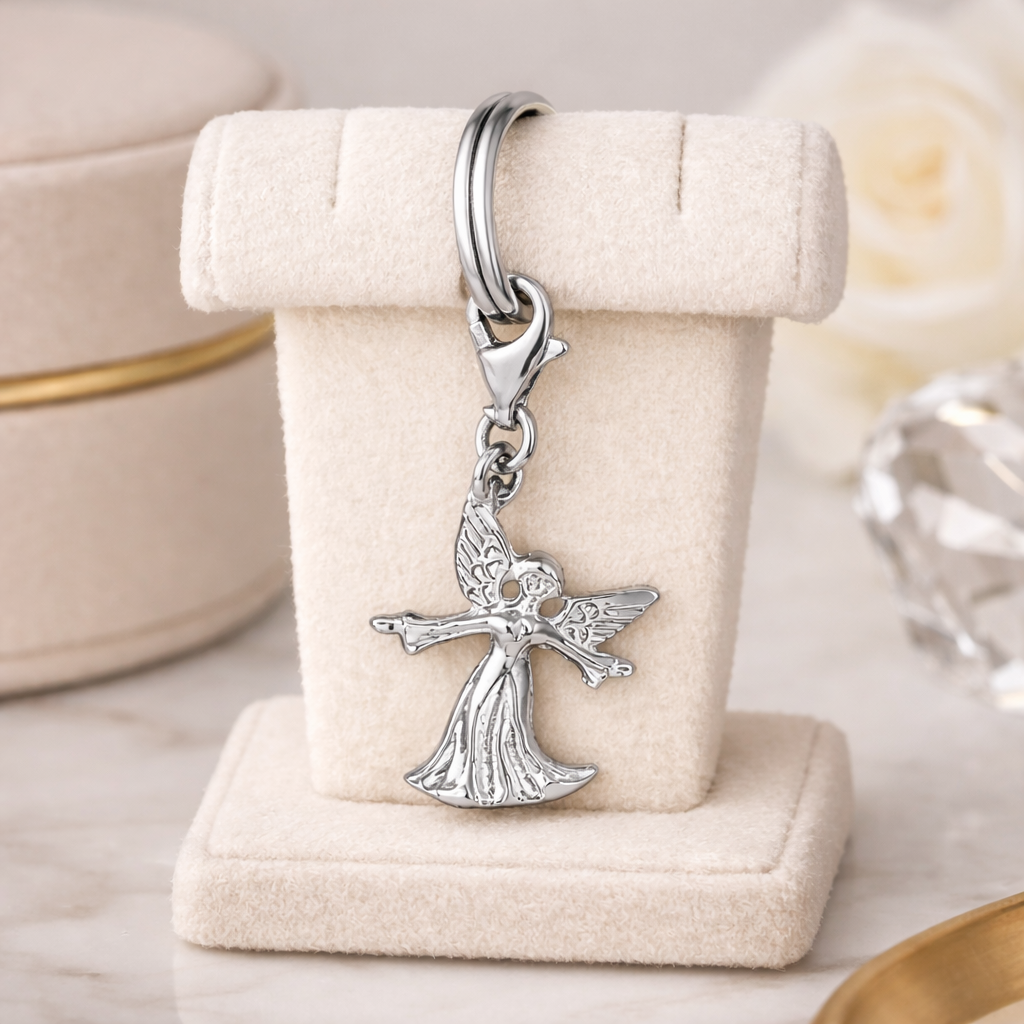 Sterling silver guardian angel charm with intricate wings and flowing dress displayed on a beige velvet stand