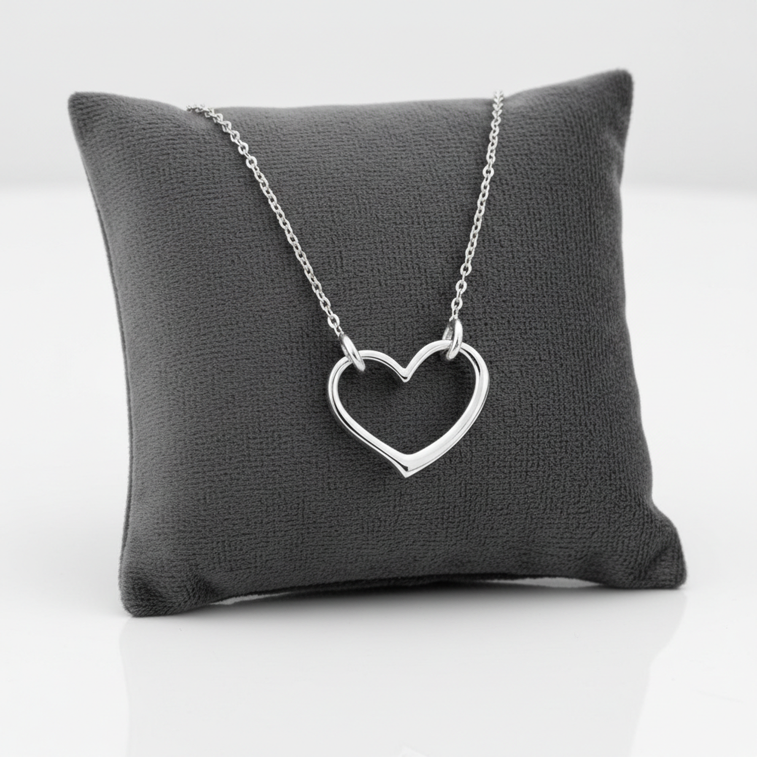 Sterling silver heart choker necklace displayed on a charcoal grey cushion by Melchior Jewellery