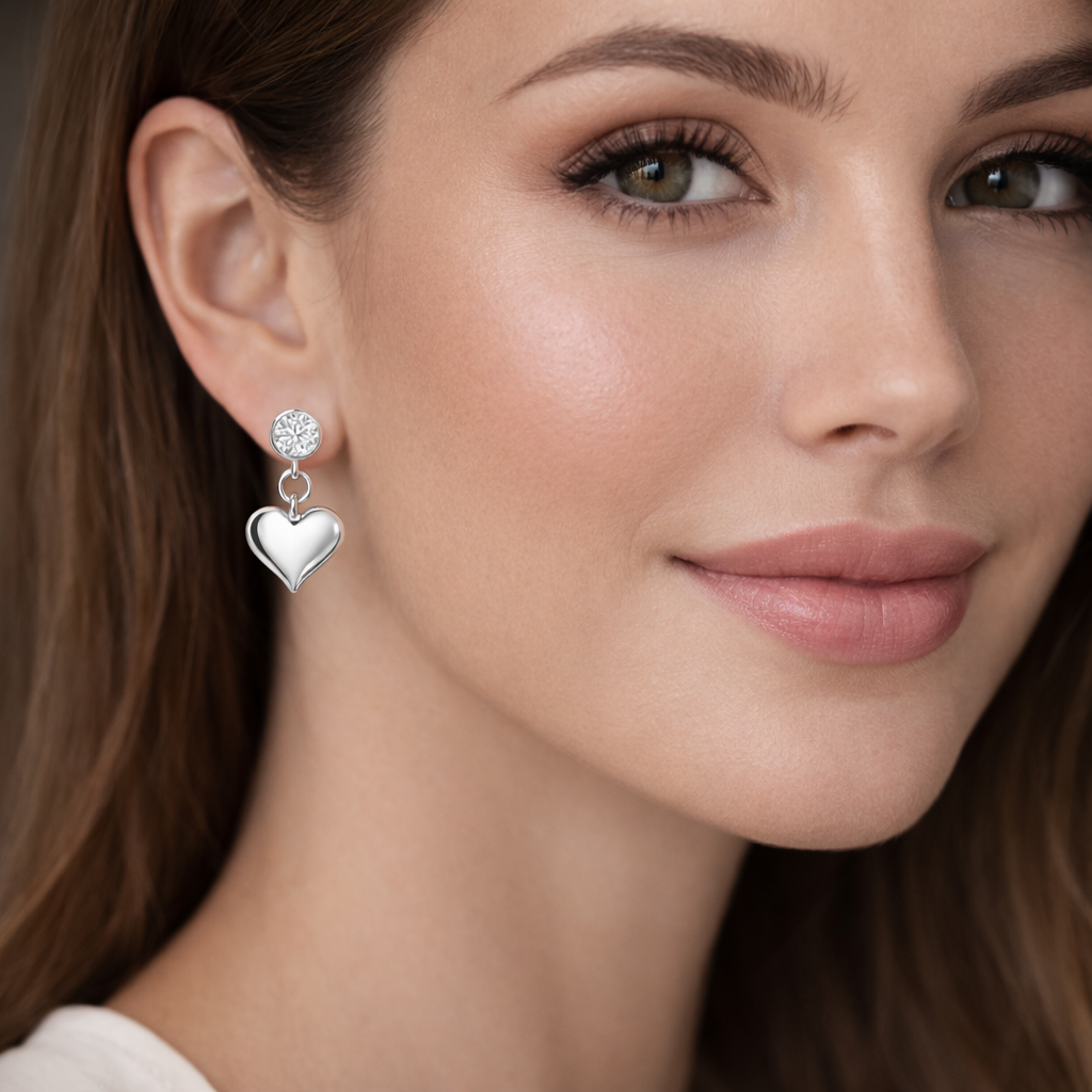 Close up of a woman wearing Melchior Jewellery sterling silver heart drop earrings with a polished finish