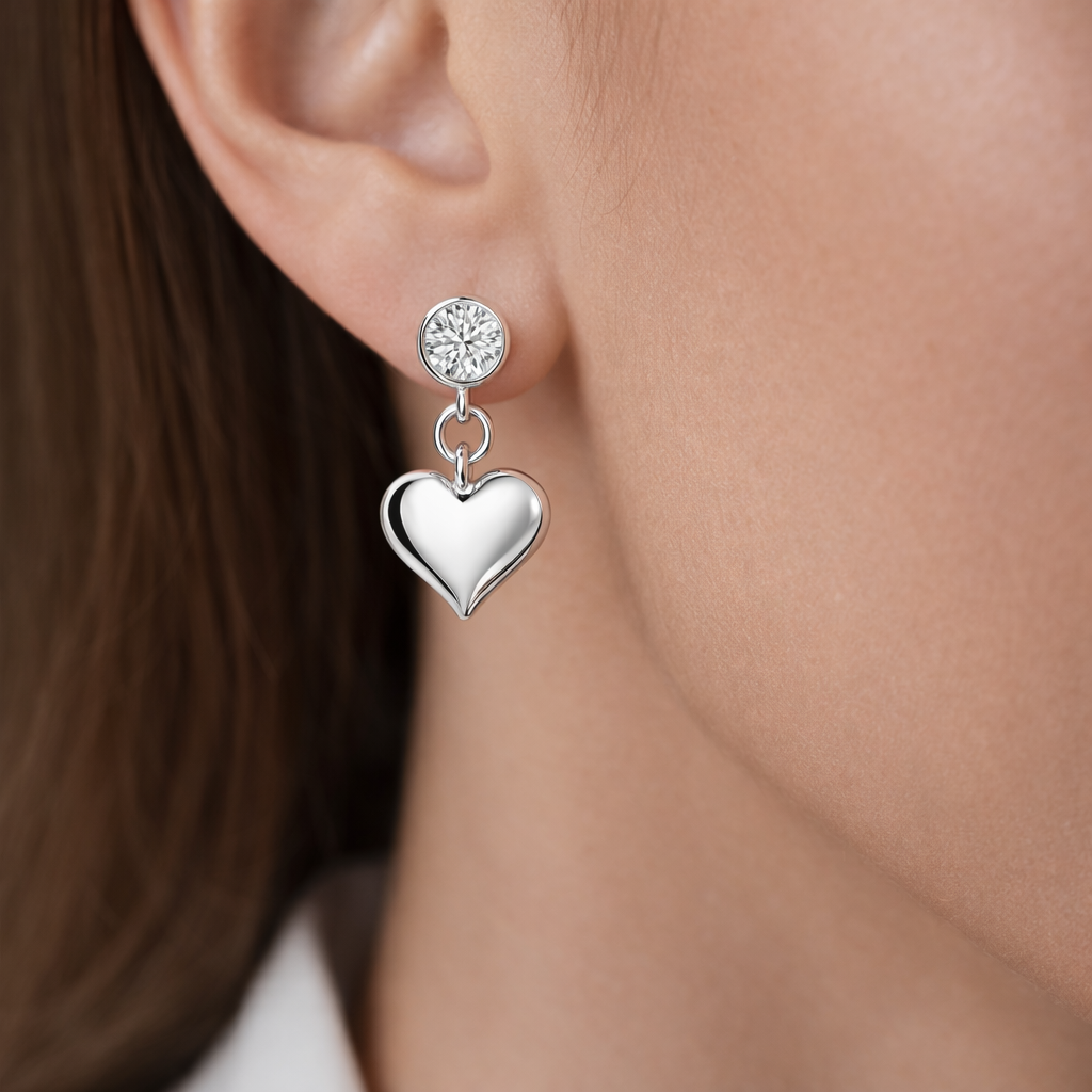 Melchior Jewellery sterling silver heart drop earrings with crystal studs on a womans ear