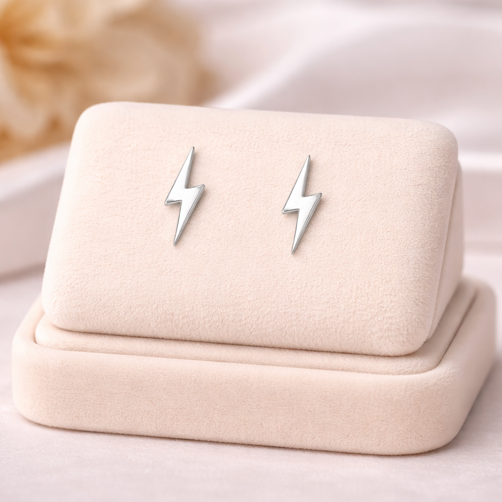 Melchior Jewellery sterling silver lightning bolt earrings with a polished finish displayed on a soft beige velvet stand