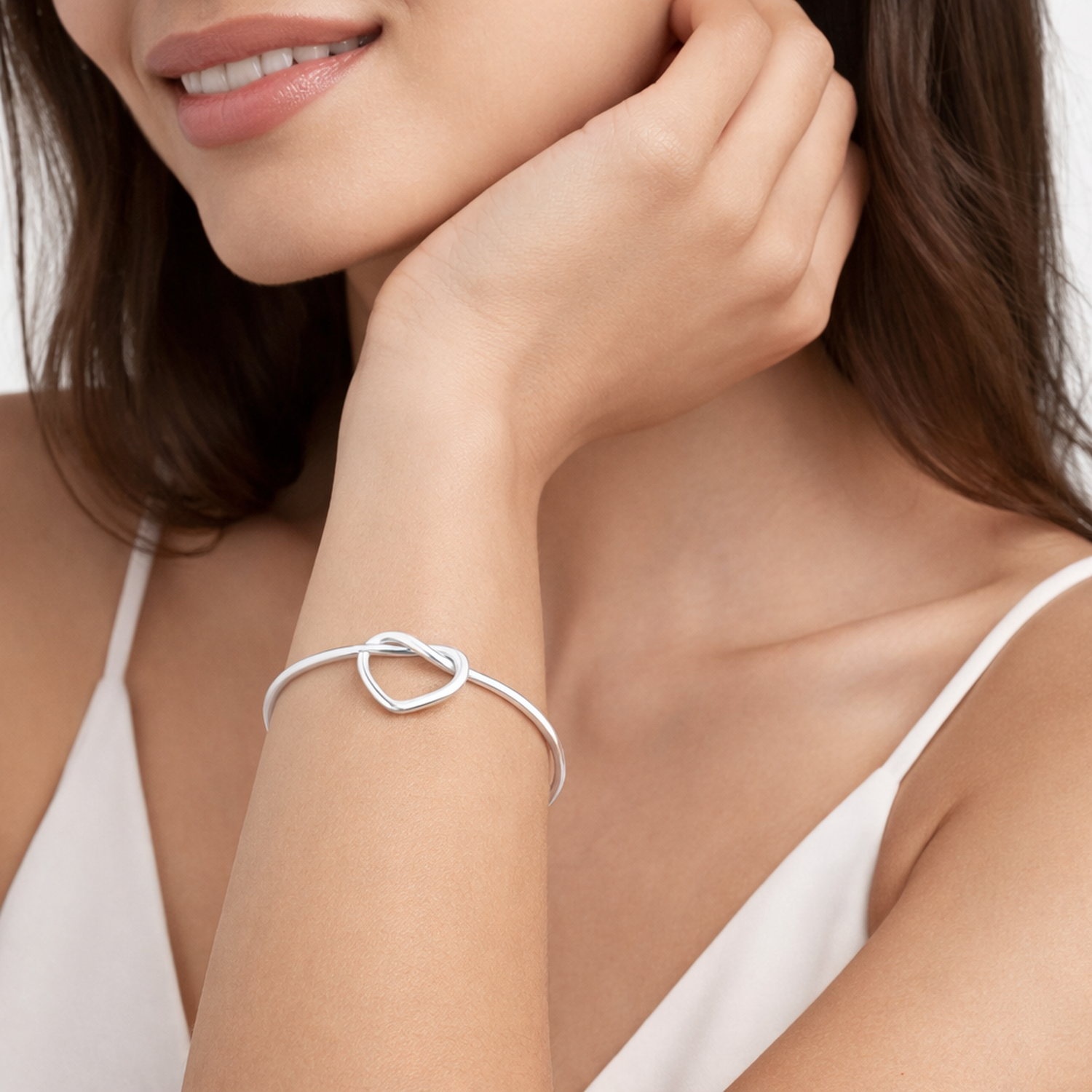 Melchior Jewellery sterling silver love knot bangle worn on wrist with white sleeveless top