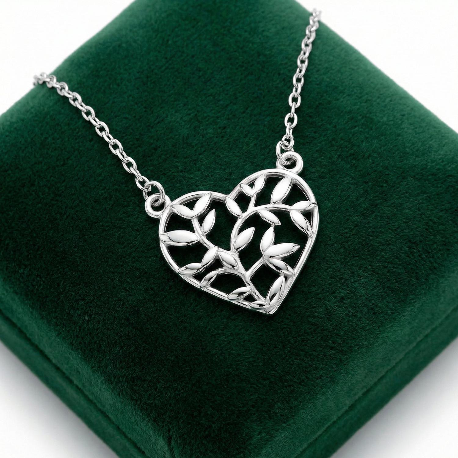 Sentiell sterling silver olive leaf pendant in heart shape on chain displayed on green velvet cushion