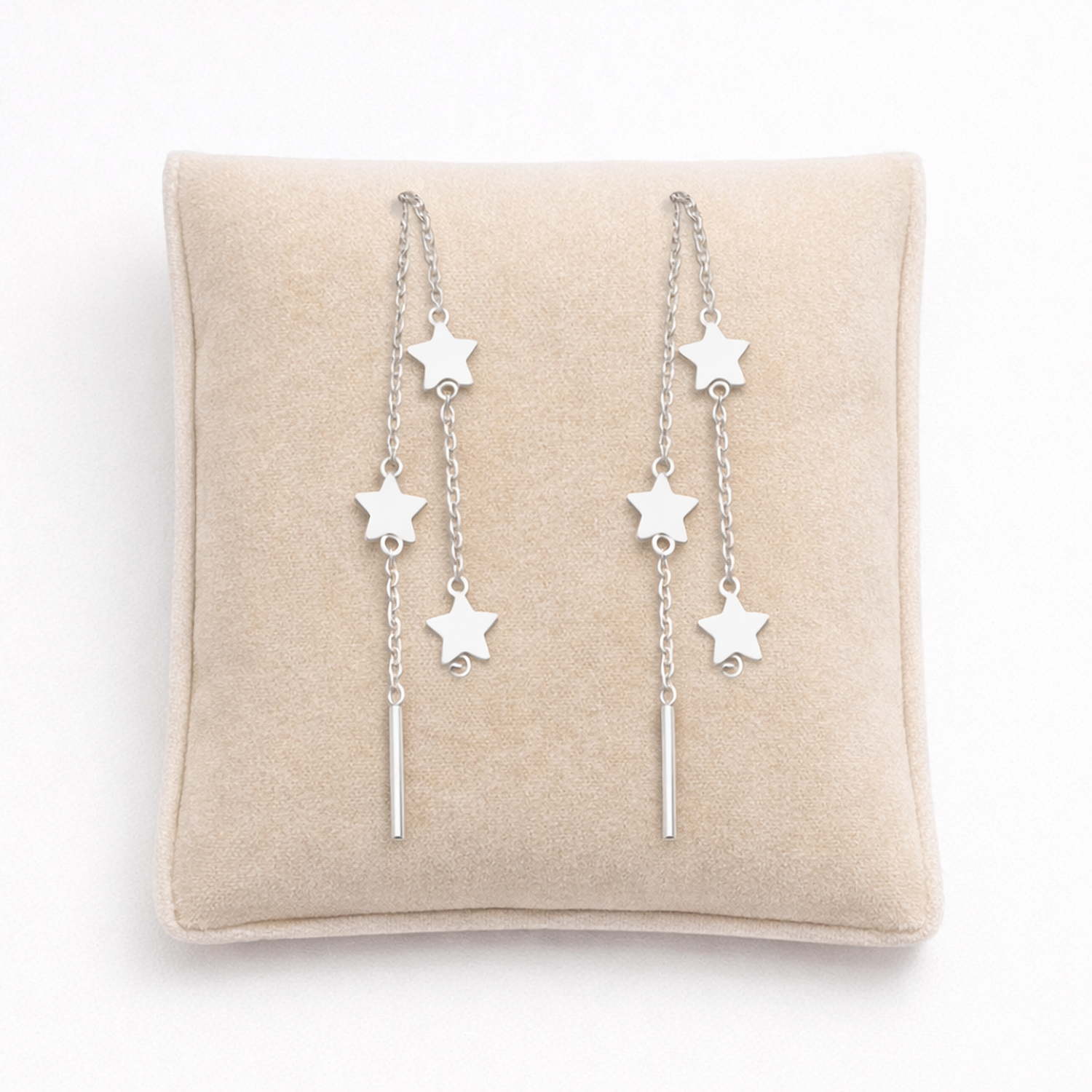 Sterling silver star threader earrings by Melchior Jewellery displayed on a beige cushion