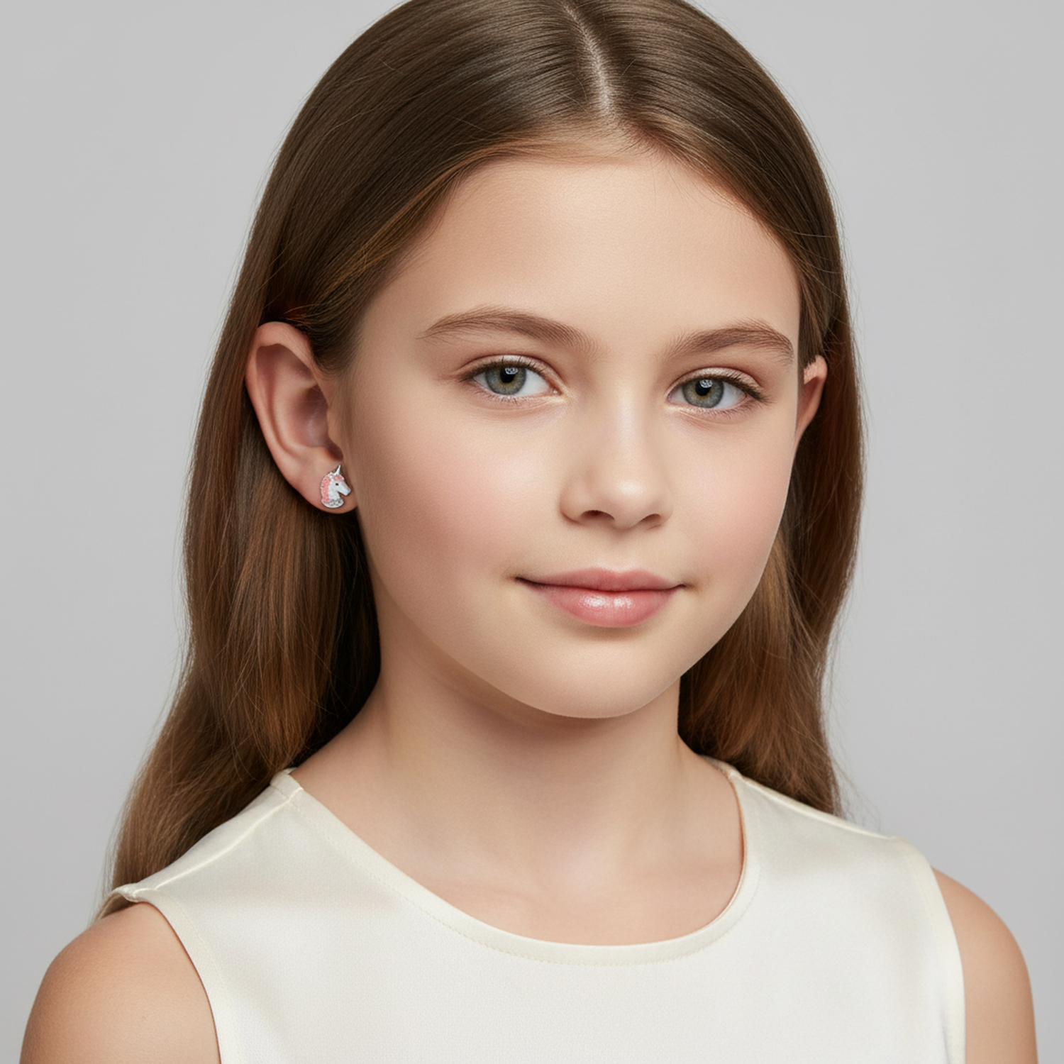 Girl wearing Melchior Jewellery sterling silver unicorn earrings for girls with long brown hair and white top