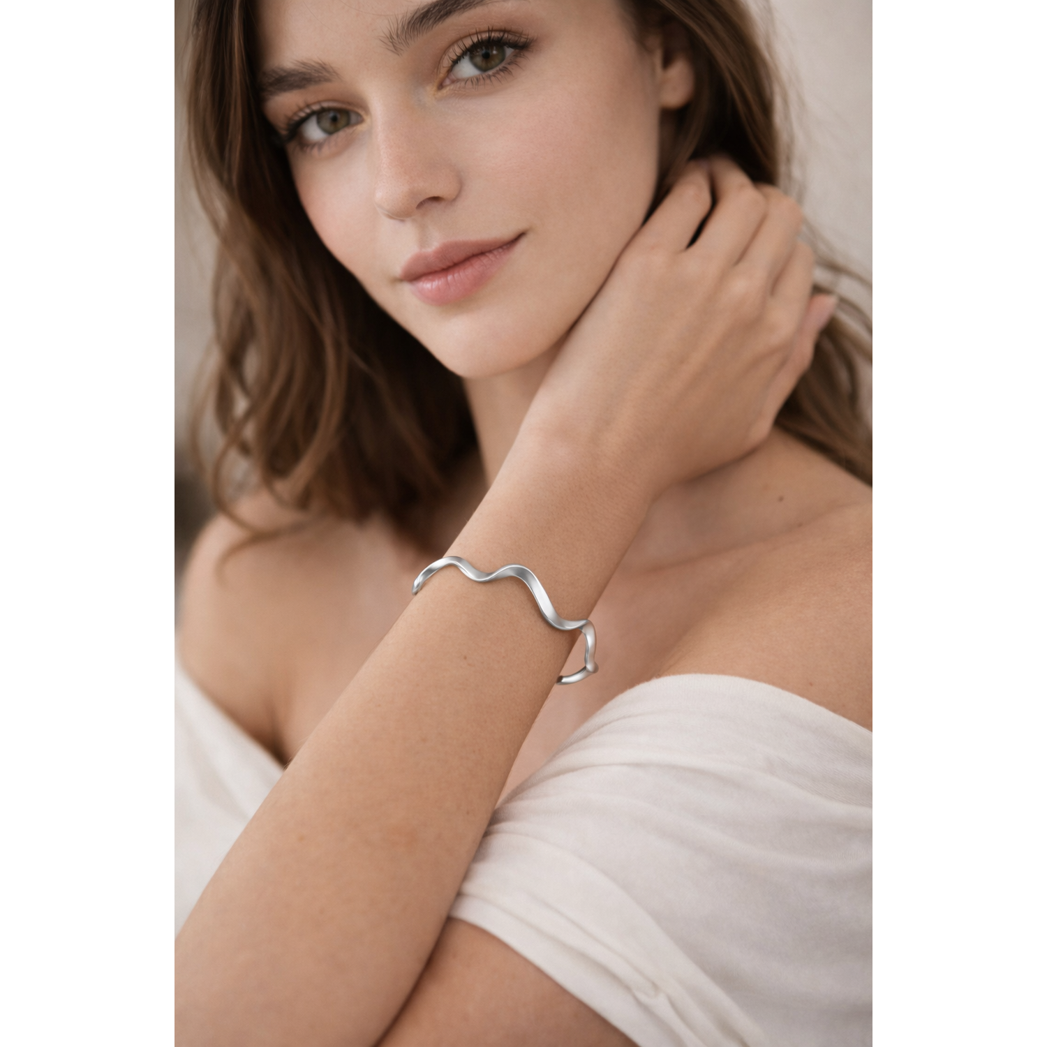 Melchior Jewellery sterling silver wave cuff bangle worn on wrist by woman in white off shoulder top