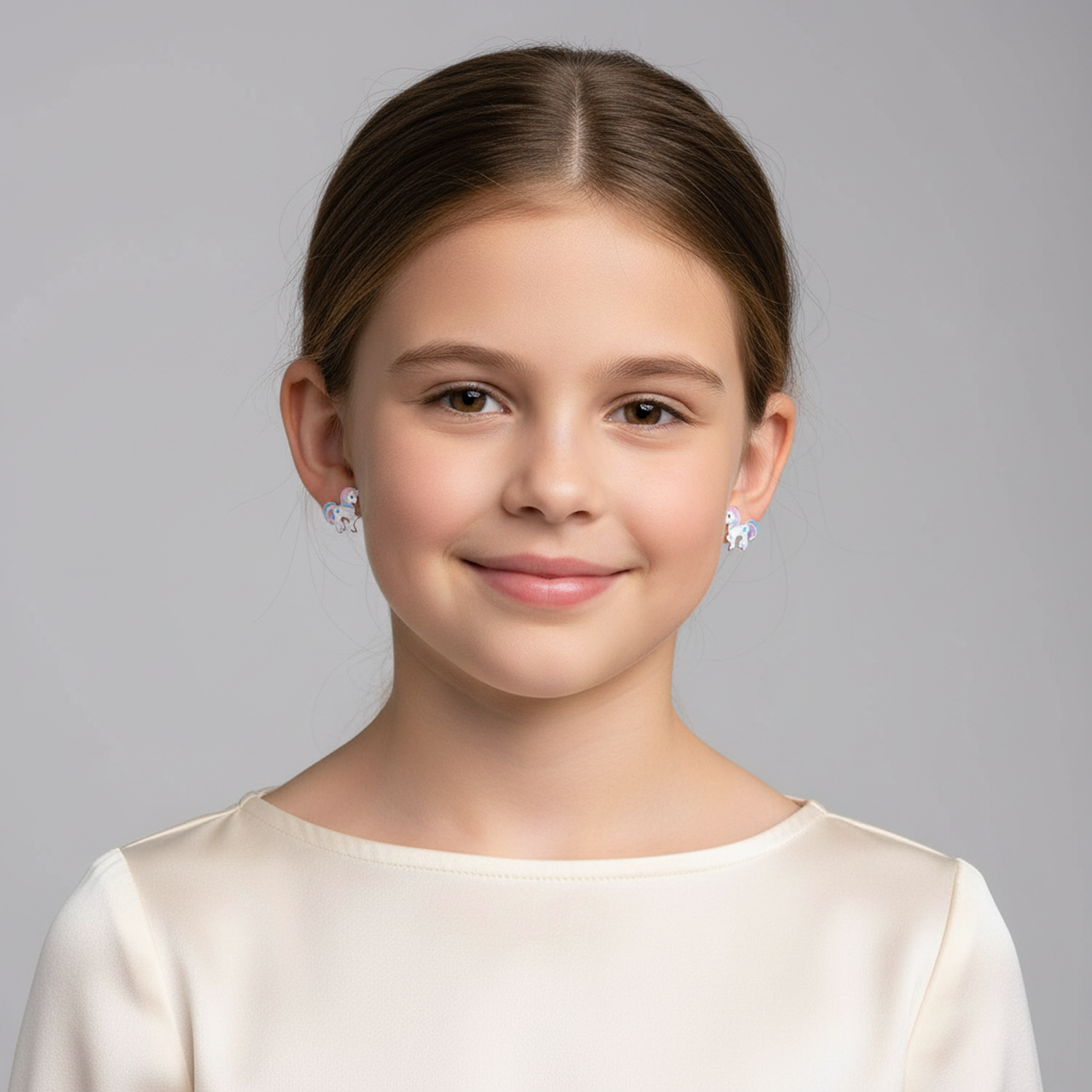 Young girl wearing Melchior Jewellery unicorn stud earrings for girls with a white top and smiling
