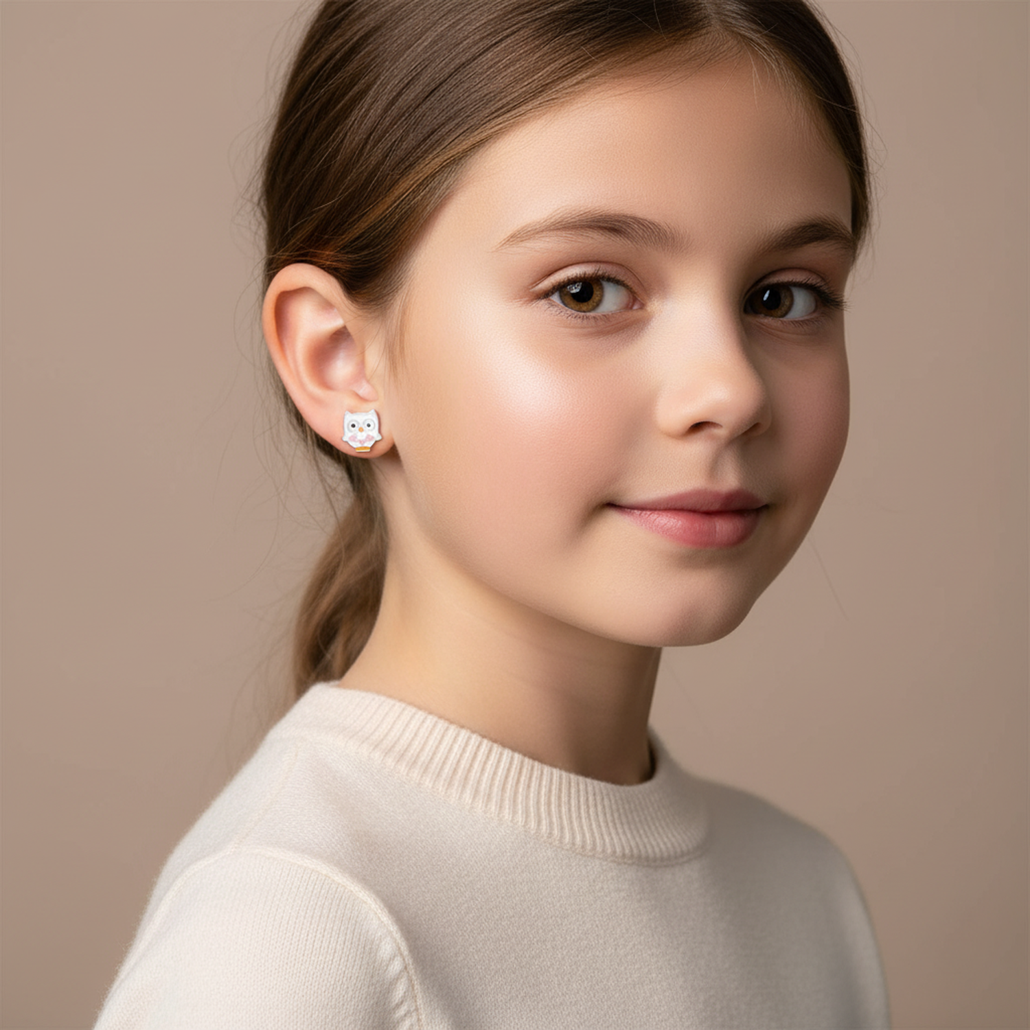 Young girl wearing white owl stud earrings for kids by Melchior Jewellery with pink and gold details