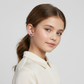 Young girl wearing purple bow stud earrings for kids by Melchior Jewellery in a white blouse