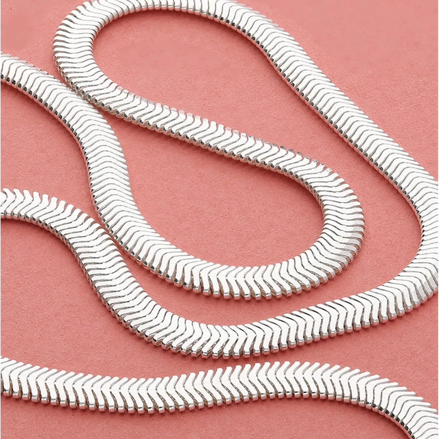 Sterling silver Diamond Cut Snake Bracelet with reflective finish on pink background for elegant style