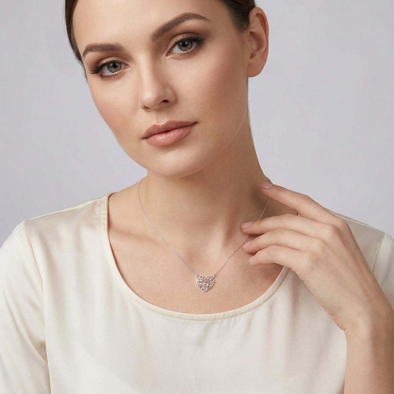 Woman wearing Sentiell sterling silver olive leaf pendant necklace with delicate chain on cream top