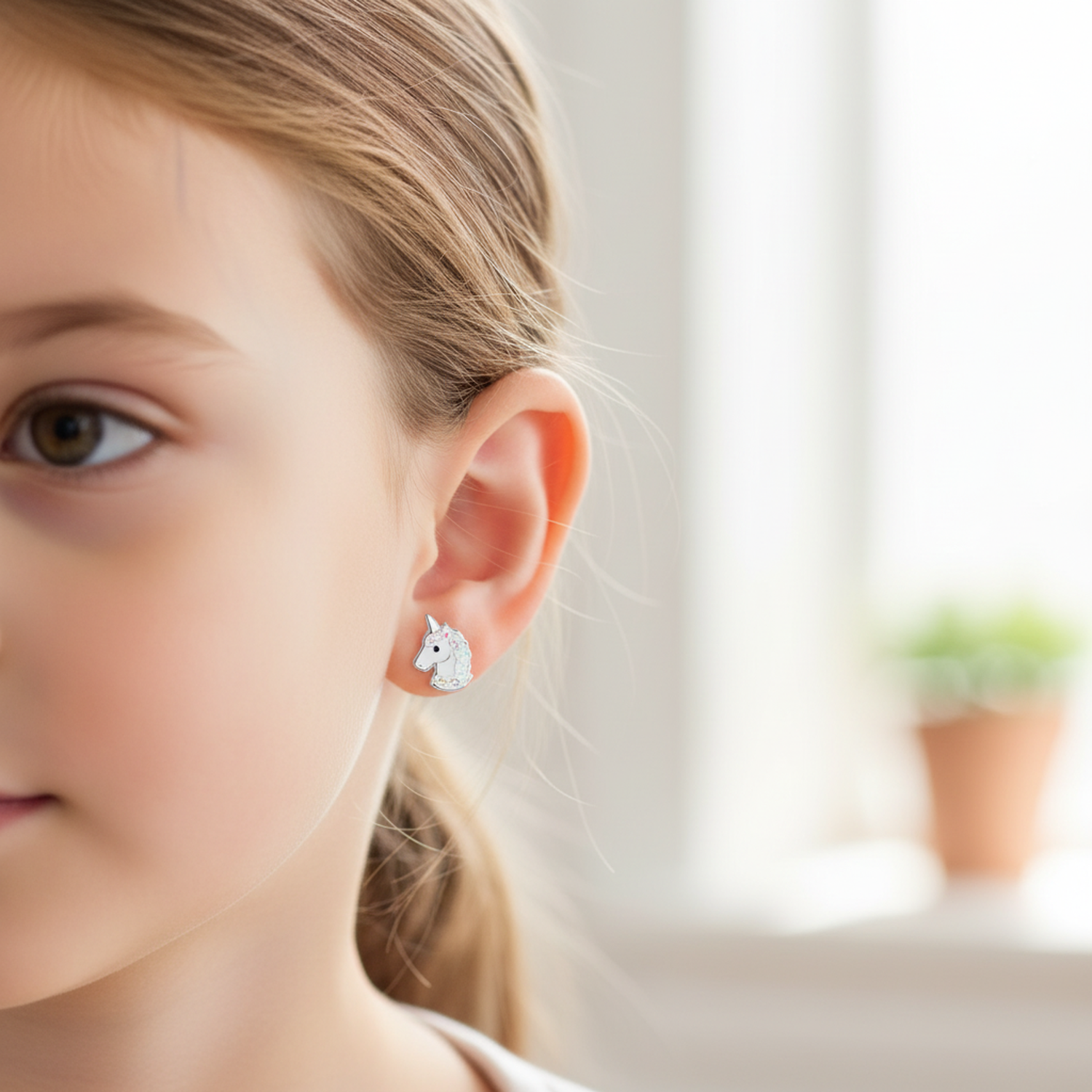 Sparkly unicorn screw back earrings for girls worn by young child from Melchior Jewellery