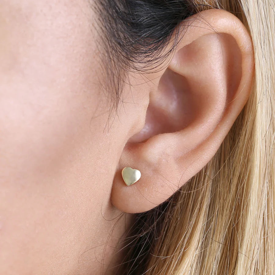 14k yellow gold heart earrings worn on ear, small elegant Melchior Jewellery studs