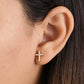 Close-up of 14k gold cross earrings worn on ear by Melchior Jewellery