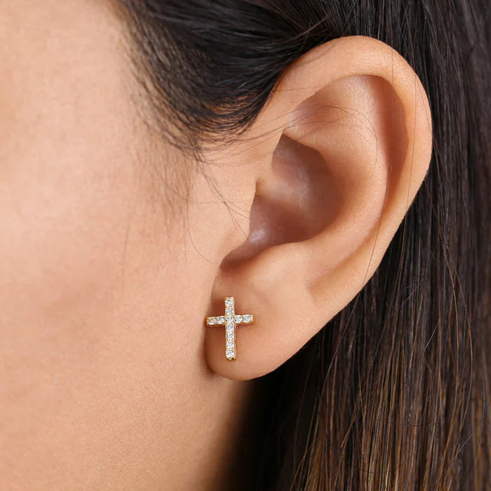 Close-up of 14k gold cross earrings worn on ear by Melchior Jewellery
