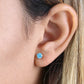 14k yellow gold blue topaz earrings worn on ear showcasing bright blue gemstone studs by Melchior Jewellery
