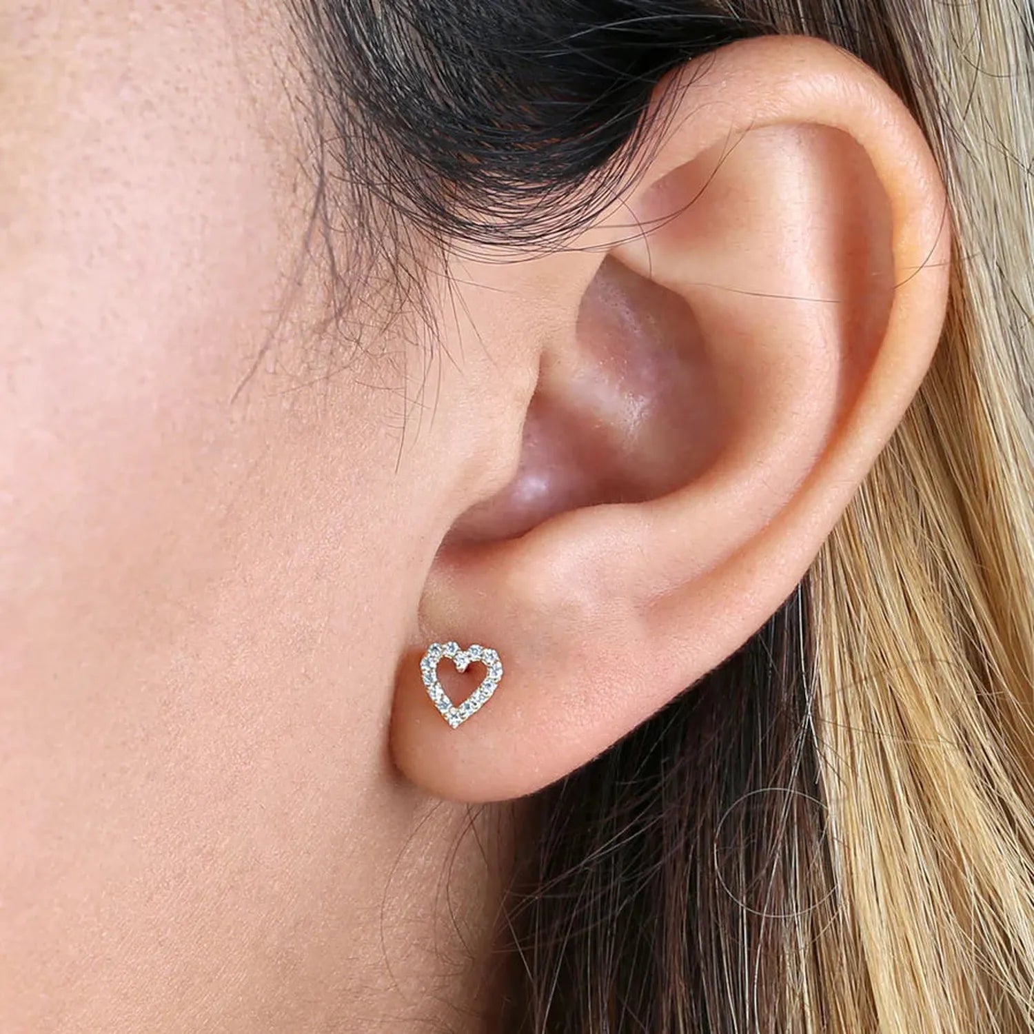 Close-up of ear wearing Melchior Jewellery heart shaped cubic zirconia studs sparkling delicately