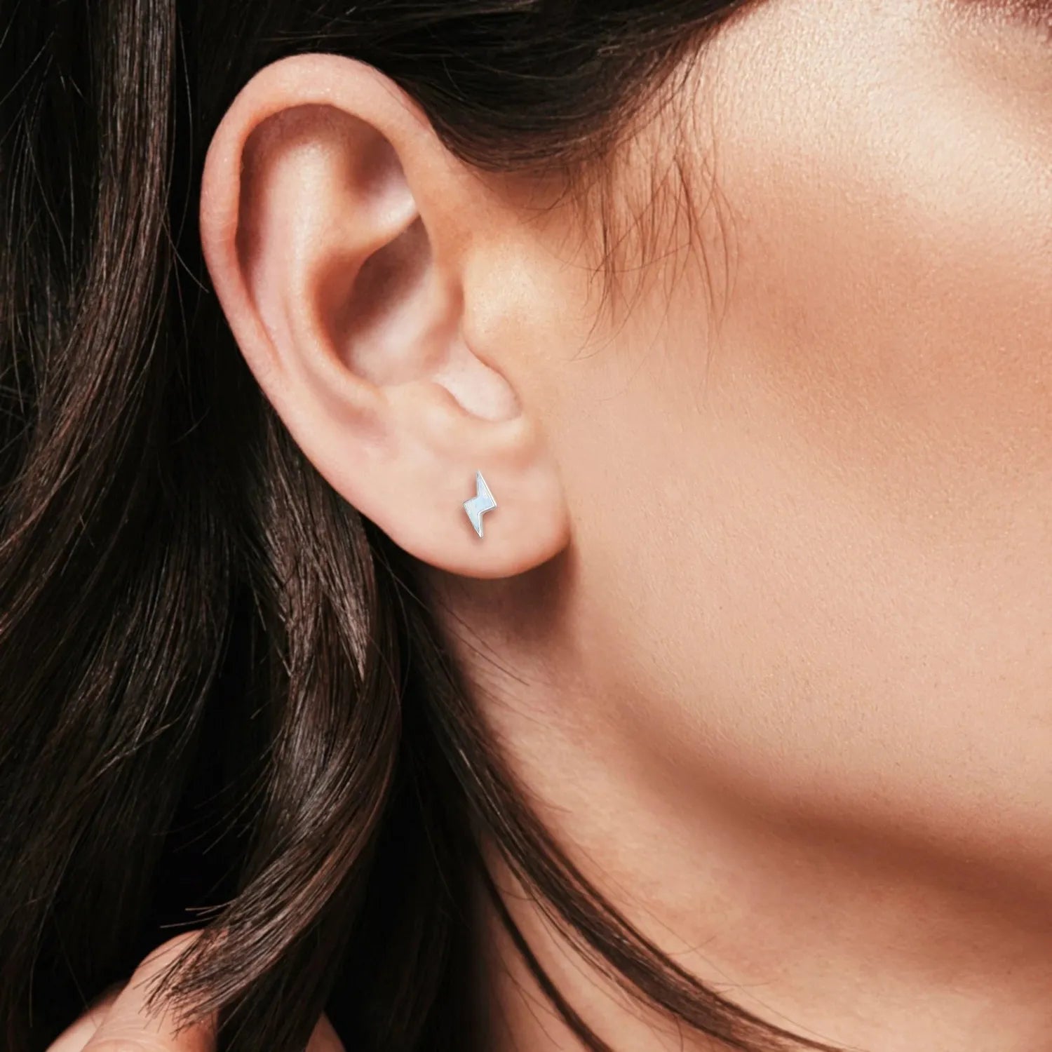 Melchior Jewellery silver white opal lightning bolt stud earrings worn on ear with dark hair